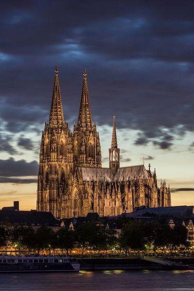 Westdeutschland Kölner Dom bei Dämmerung mit dramatischem Himmel und beleuchtetem Vordergrund.