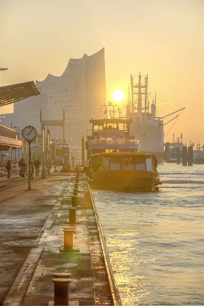 Norddeutschland Hafenansicht mit Booten, Sonnenaufgang und moderner Architektur im Hintergrund.